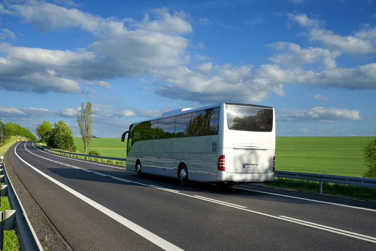 First class bus on the road passing green fields